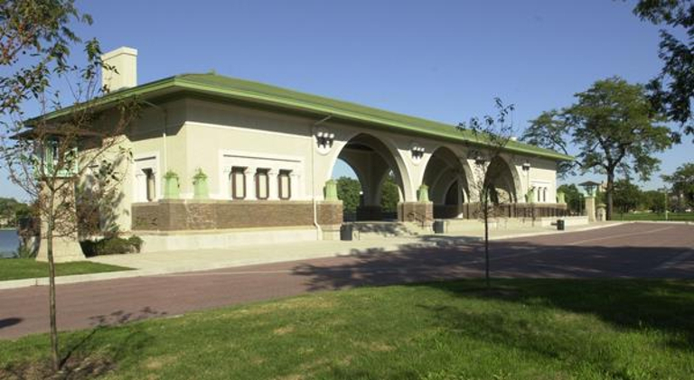 Cream-colored pavilion with green tile roof and arched openings.