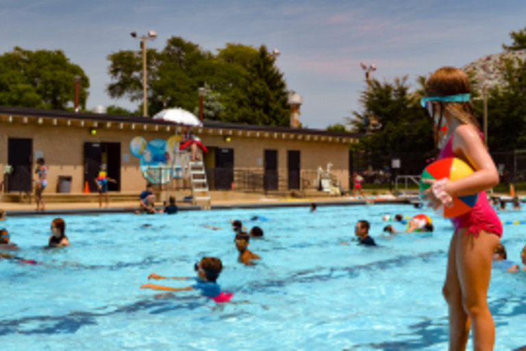 Child with beach ball at edge of crowded public pool.