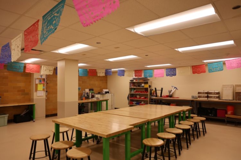 Classroom with long tables and colorful papel picado.