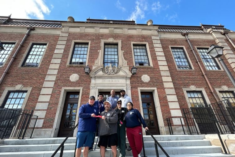 Group photo of seven people on the steps of a brick building.