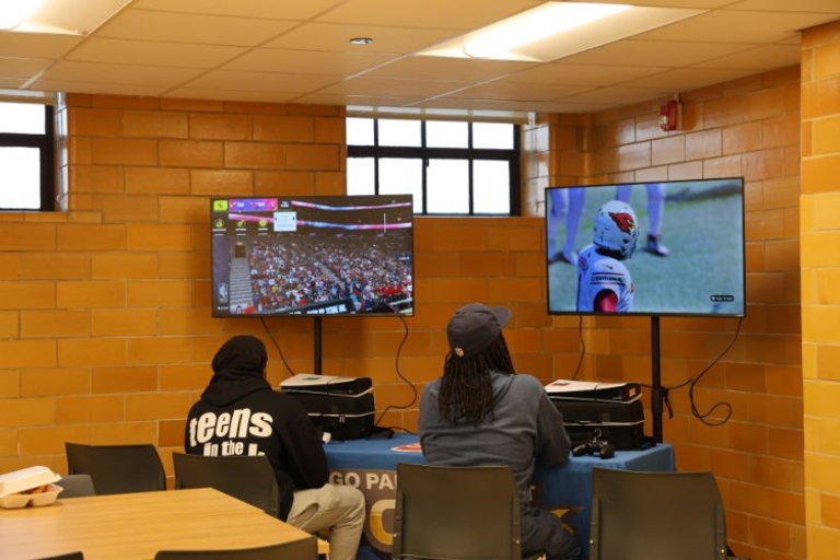 Two teens playing video games on separate TVs.