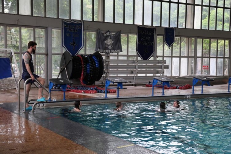 Coach watches swimmers in an indoor pool.