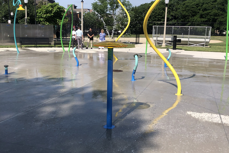 Splash pad with colorful pipes spraying water on a sunny day.