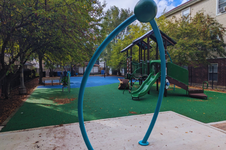 Playground with a blue arch, green slide, and playhouse.