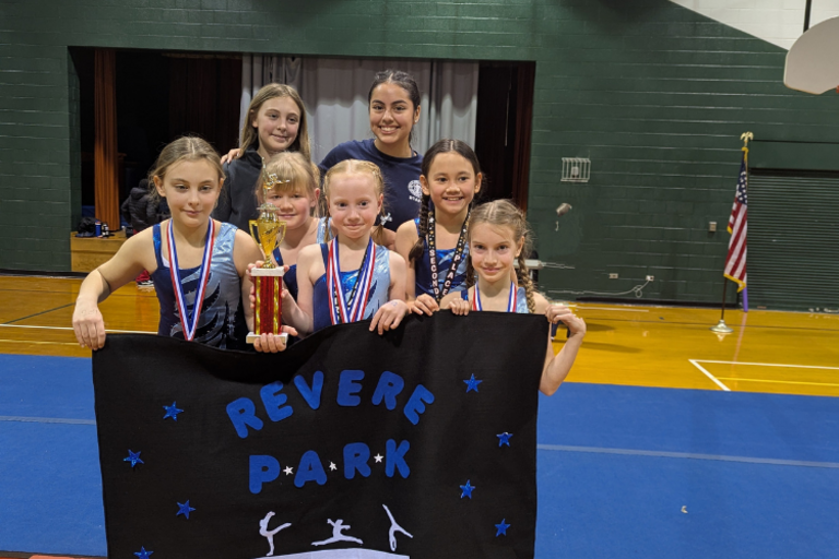 Group of gymnasts holding award and Revere Park banner.