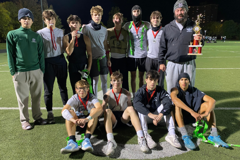 Photograph of a flag football team with their coach and trophy.