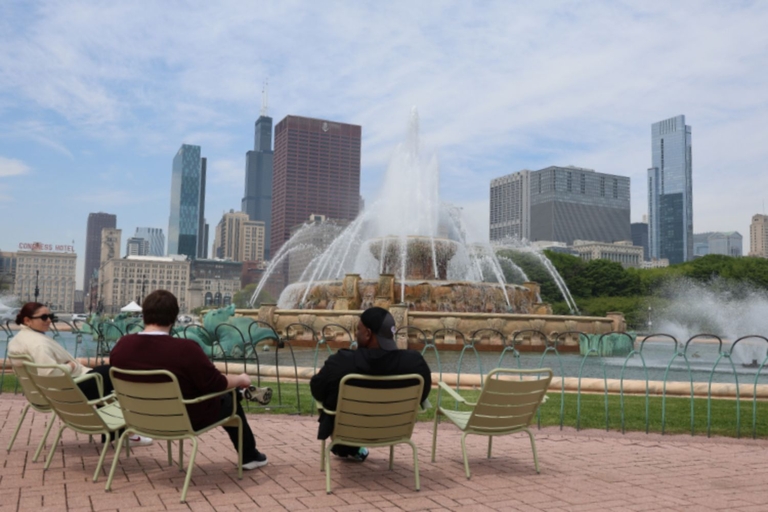 People sit on chairs in front of the Buckingham Fountain with the Chicago skyline in the background.