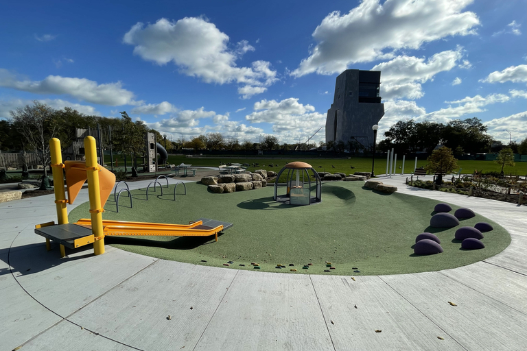 A modern outdoor playground with climbing equipment, under a blue sky with fluffy clouds.