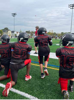 Youth football team kneeling on the field.