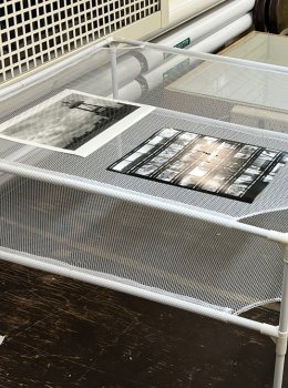 Photo prints drying on mesh rack.