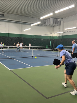 Pickleball players volley on an indoor court.