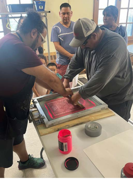 Man using squeegee to create silkscreen print.