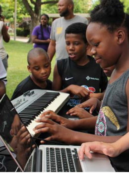 Children play music with a keyboard and laptop.