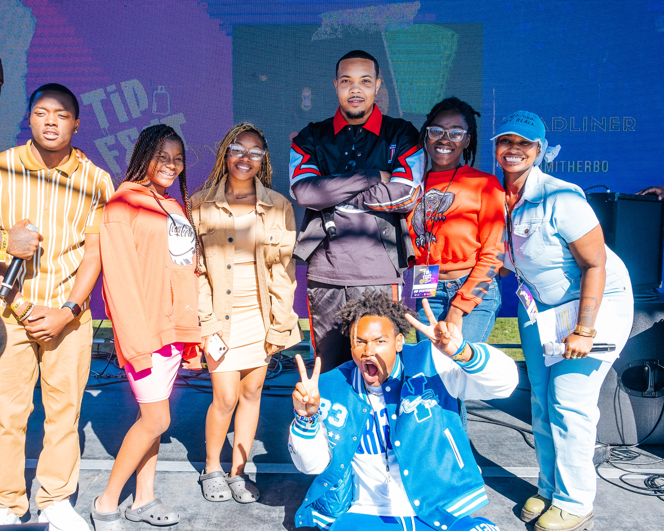Group photo of seven people posing for a picture on stage.