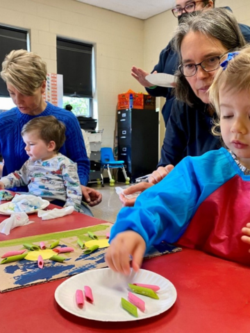 Toddlers create art with colorful pasta.