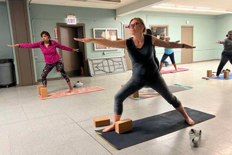 People practicing the Warrior II yoga pose in a studio.
