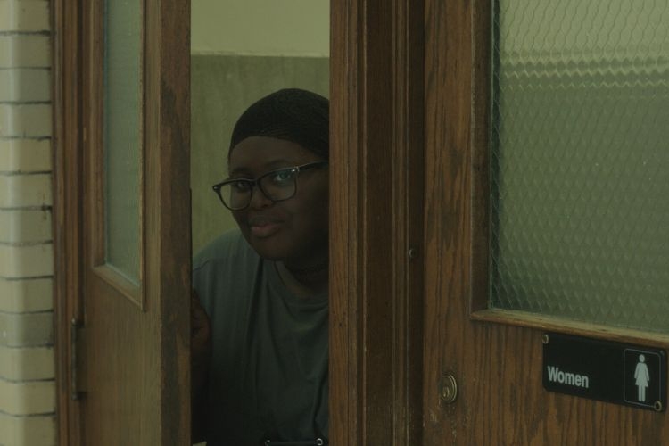 A person peeks out from a women's restroom door.