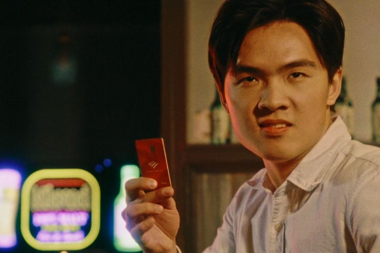Man holding a red credit card in a bar.