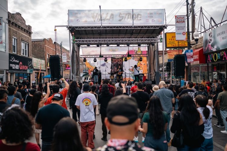 Crowd watching band perform on outdoor stage at street festival.