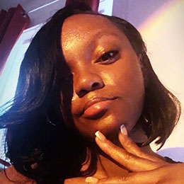 Close-up of a young woman with a thoughtful expression, hand on chin.