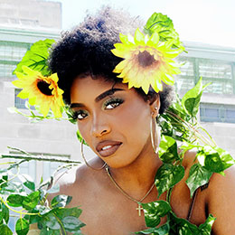 Woman with sunflowers in her hair and vines around her shoulders.