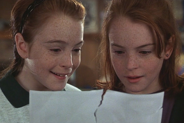 Twin girls examining a torn piece of paper.