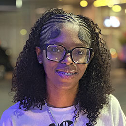 Smiling woman with braids and glasses.