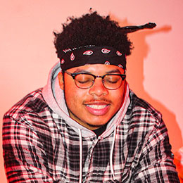Smiling young man wearing glasses and bandana.