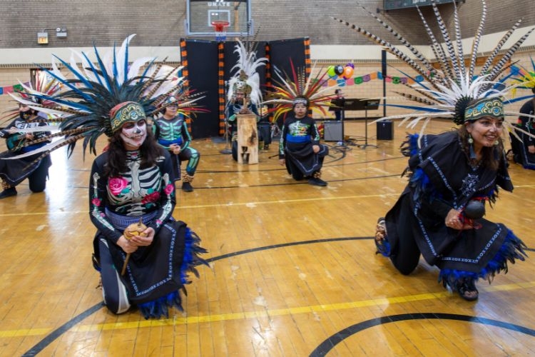 Día de Muertos Aztec dancers on a basketball court.