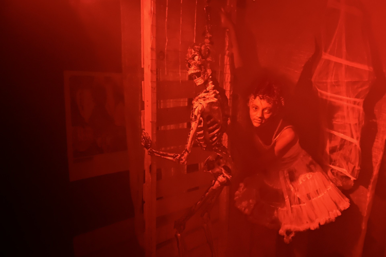 A skeleton and a person in a red-lit room.