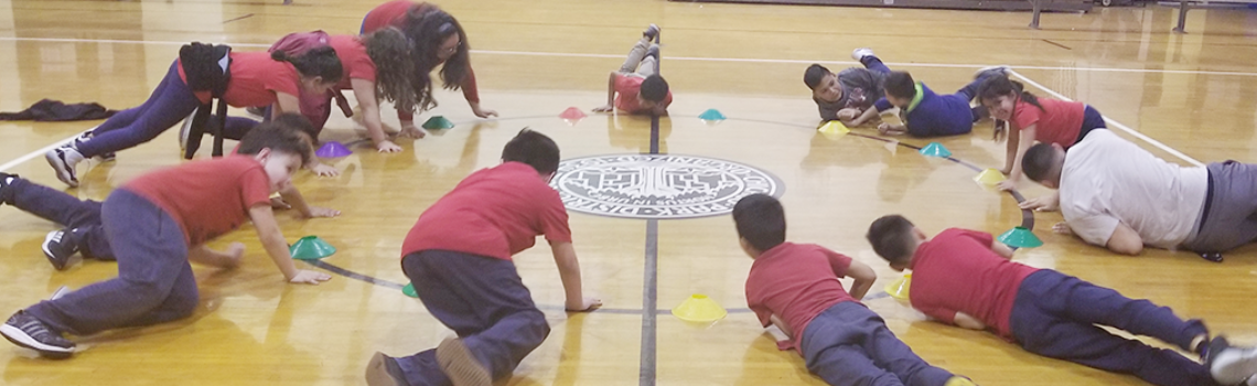 Children lay on gym floor with colorful cones, as part of a recreation activity.