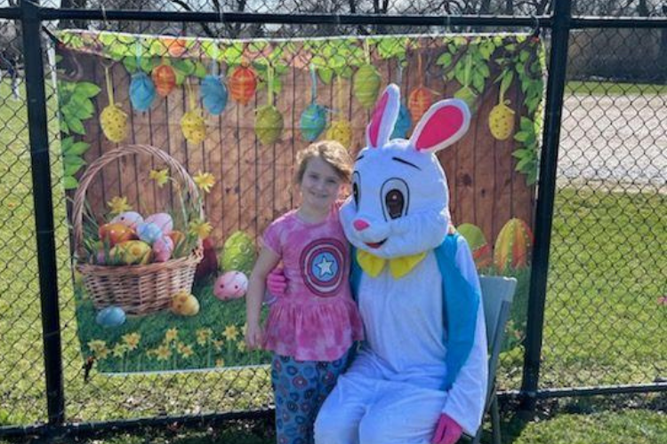Girl poses with Easter bunny mascot.