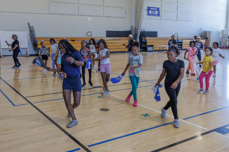 Photograph of girls indoors practicing color guard.