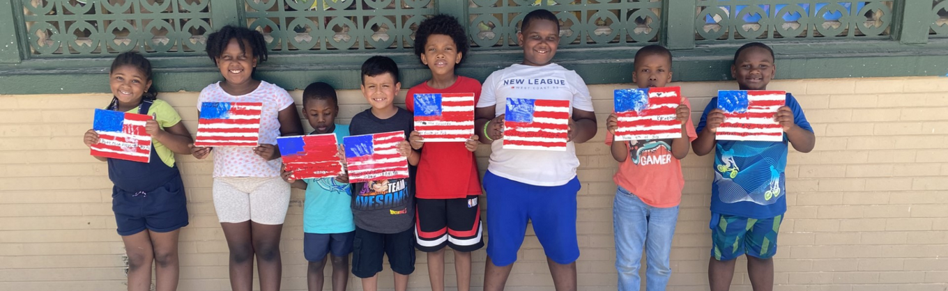 Eight smiling children hold up handmade American flag paintings in a row.