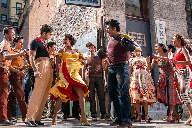 A group of people in mid-century attire dancing on a city street in a promotional film still.