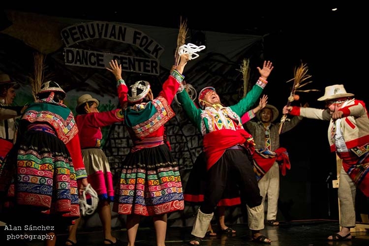 Photograph of dancers in traditional Peruvian costumes performing on a stage.