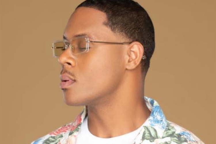 Profile photograph of a man wearing clear-framed glasses and a floral shirt.