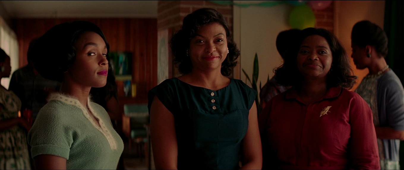 Three women in 1960s attire smile at a party in this film still.
