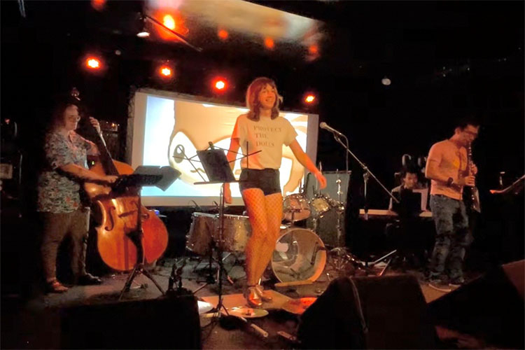 Photograph of a band performing on stage in a dimly lit club.