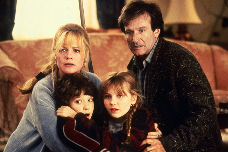 A worried woman and man embracing two children in a living room, in a film still from Jumanji.