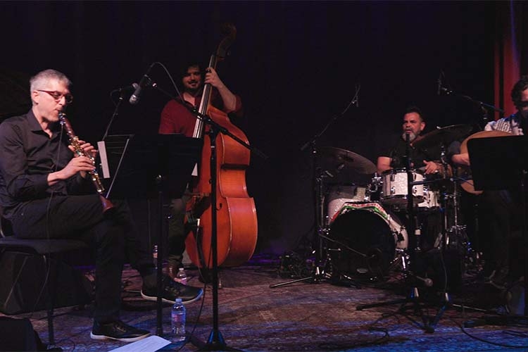 A four-piece jazz band performs on a dimly lit stage.