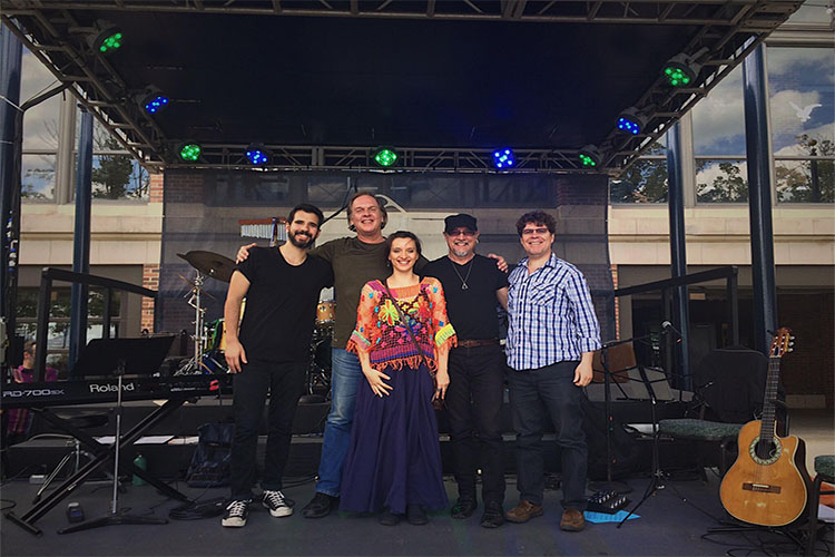 Photograph of a band standing on a stage with musical instruments.