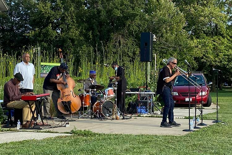 Photograph of a jazz band playing outdoors in a park setting.