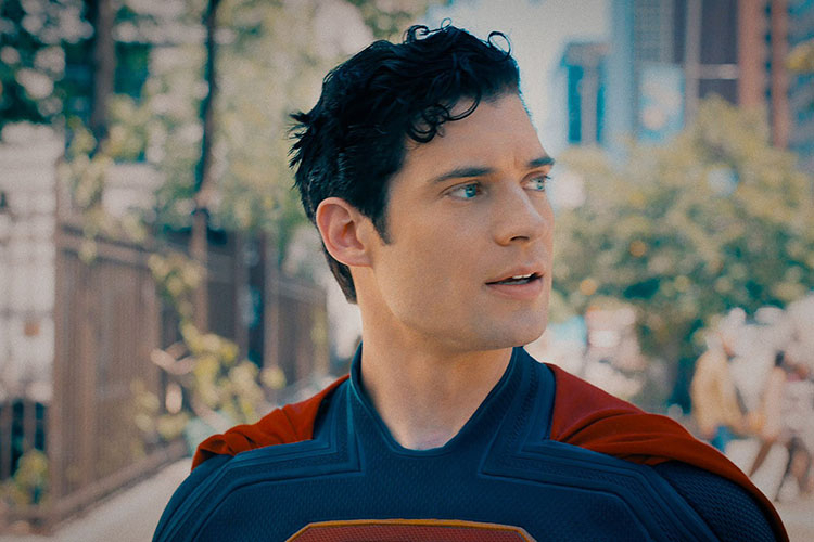 Photograph of actor David Corenswet in a Superman costume, looking to the side outdoors.