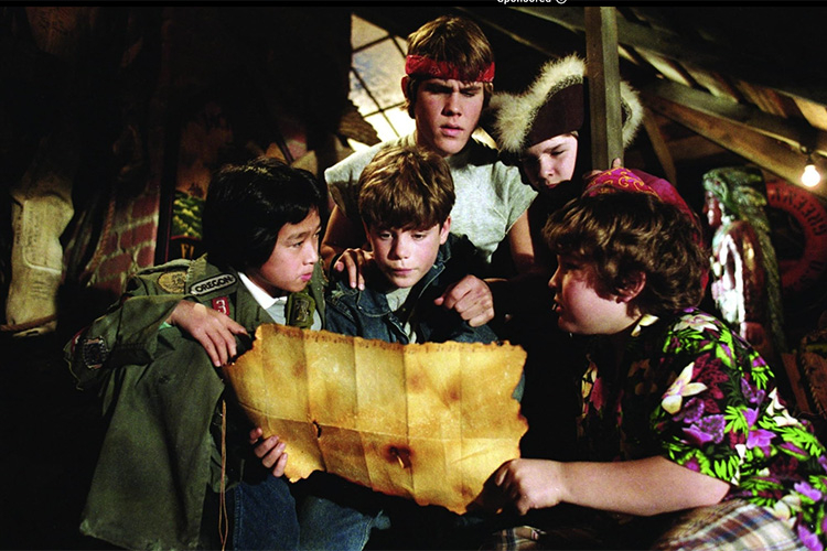 A group of five young friends huddled together in a dimly lit space, examining an old treasure map.