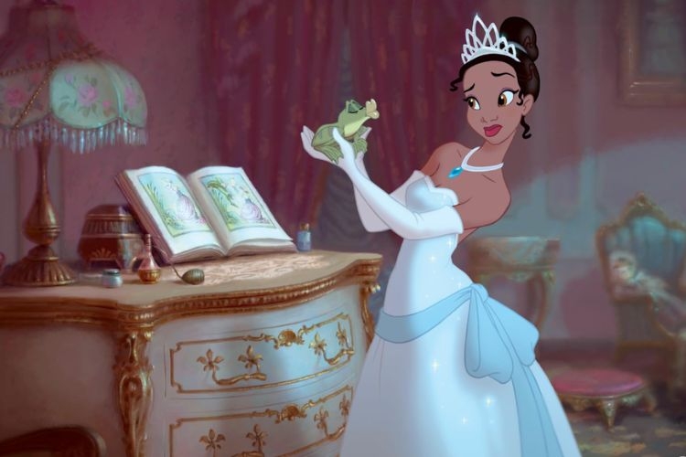 Tiana in a white gown and tiara holds a small frog in a vintage-style bedroom.