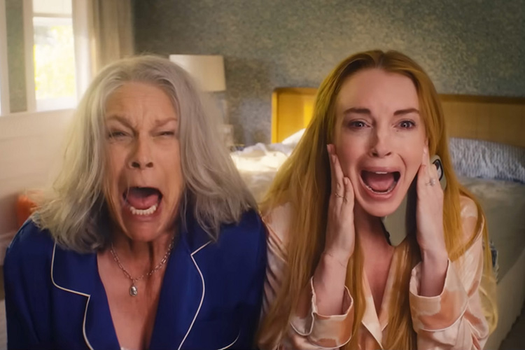 Two women in pajamas with shocked expressions scream in a bedroom.