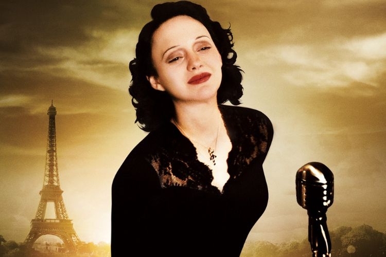 A woman in a black dress singing into a vintage microphone with the Eiffel Tower in the background.