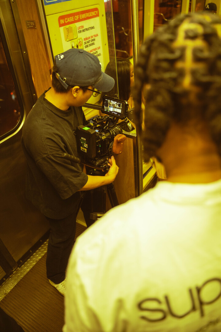 A person with a camera records inside a train, with another person in the foreground.