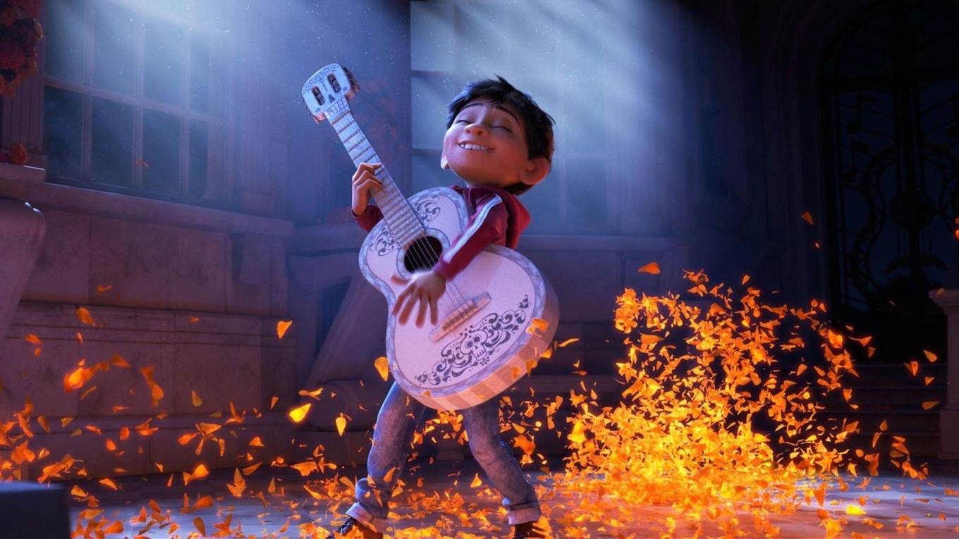 A young boy with a joyful expression playing a decorative white acoustic guitar amidst orange petals.